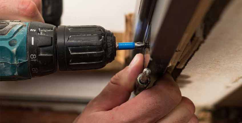 handyman fixing a piece of furniture with screwdriver