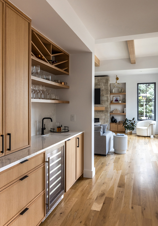 Built-in home bar with natural wood cabinetry and floating shelves — warm and inviting design by Denver-based designers